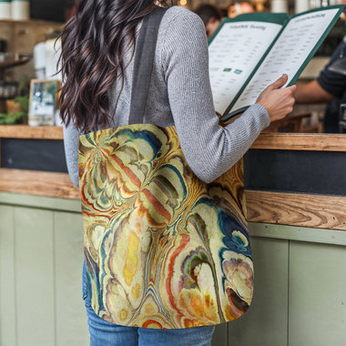 Baroque Tapestry Bag, Parisian Style Woven Tote hanging from the shoulder of a woman reading a menu at a restaurant counter.